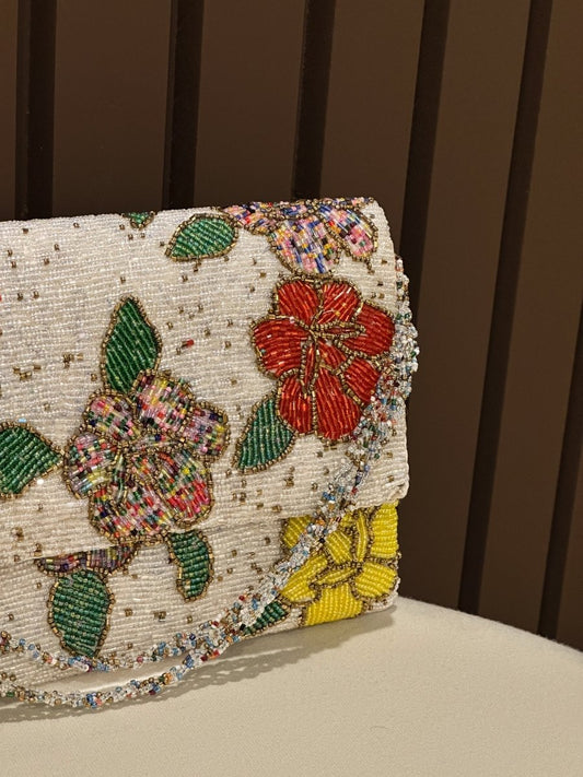 Hand-beaded white floral clutch purse with red and yellow embroidery by Amal Ayub
