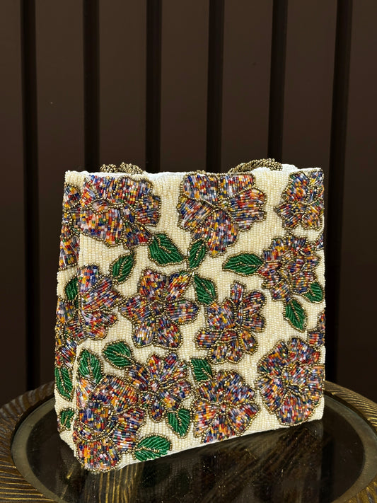  A handcrafted cream beaded handbag with multi-colored floral patterns, green leaves, and braided bronze handles - Designer Accessories by Amal Ayub