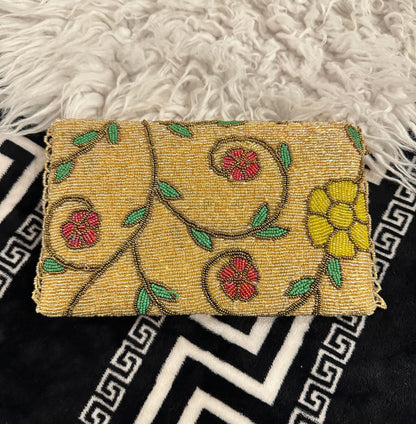 A premium handmade gold and brown structured evening bag featuring a fully embellished beaded base with stunning blue-and-gold and yellow floral designs. Designed by Amal Ayub, this luxury purse is a perfect wedding accessory representing high-end Ladies Hand Bags Pakistan