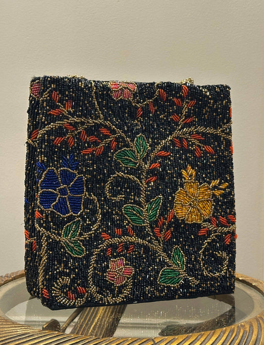 Handcrafted black beaded handbag featuring delicate gold vine patterns, green leaves, and blue and yellow floral embroidery - Designer Accessories by Amal Ayub
