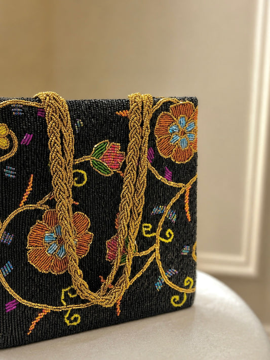 Handcrafted black beaded tote bag with vibrant vine motifs and gold braided straps by Amal Ayub