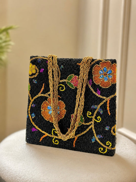 Handcrafted black beaded tote bag with vibrant vine motifs and gold braided straps by Amal Ayub