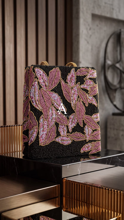Amal Ayub black hand-beaded box bag with pink and lavender leaf beadwork and gold knot handle