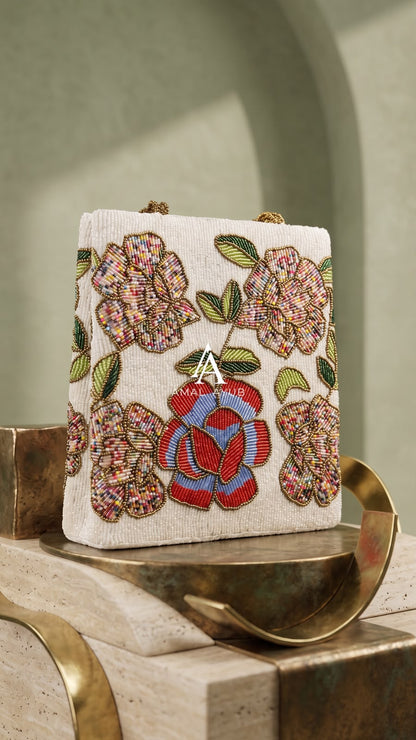 Amal Ayub white embellished handbag featuring handcrafted red, blue, and pastel floral beadwork with braided gold handles