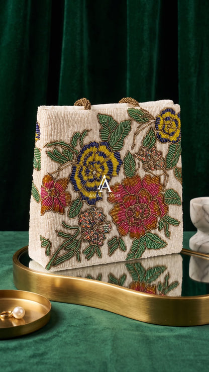 Amal Ayub ivory hand-embellished box handbag with pink, blue, and yellow floral beadwork and gold knot handle