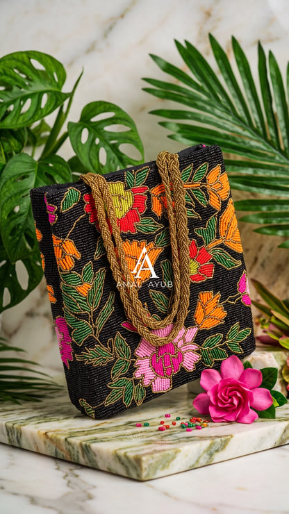 Amal Ayub black handmade bag with handcrafted pink, orange, and green floral beadwork and braided gold handles