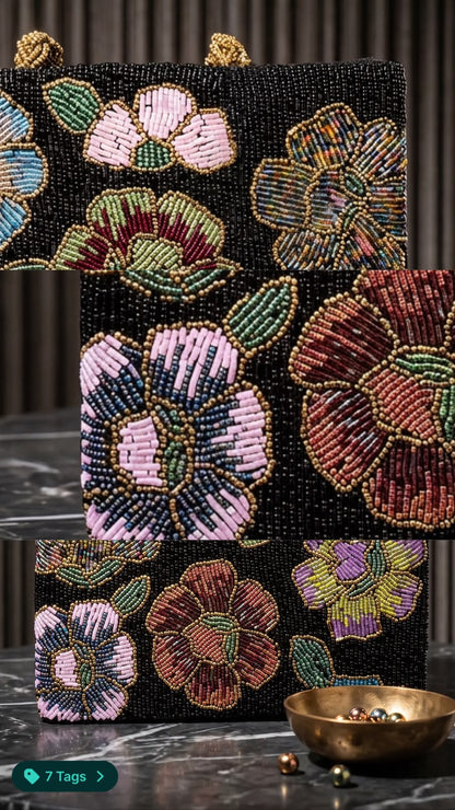 Close-up view of Amal Ayub hand-embroidered glass seed bead flowers in pink, burgundy, and lavender on a black canvas