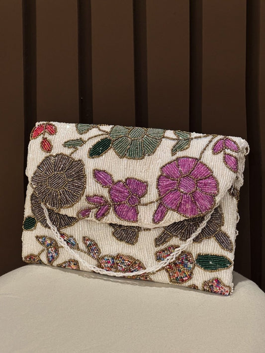 Hand-beaded floral clutch bag with purple and pink embroidered flowers on a cream base by Amal Ayub