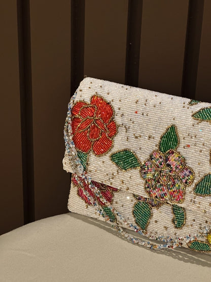Hand-beaded white floral clutch purse with red and yellow embroidery by Amal Ayub